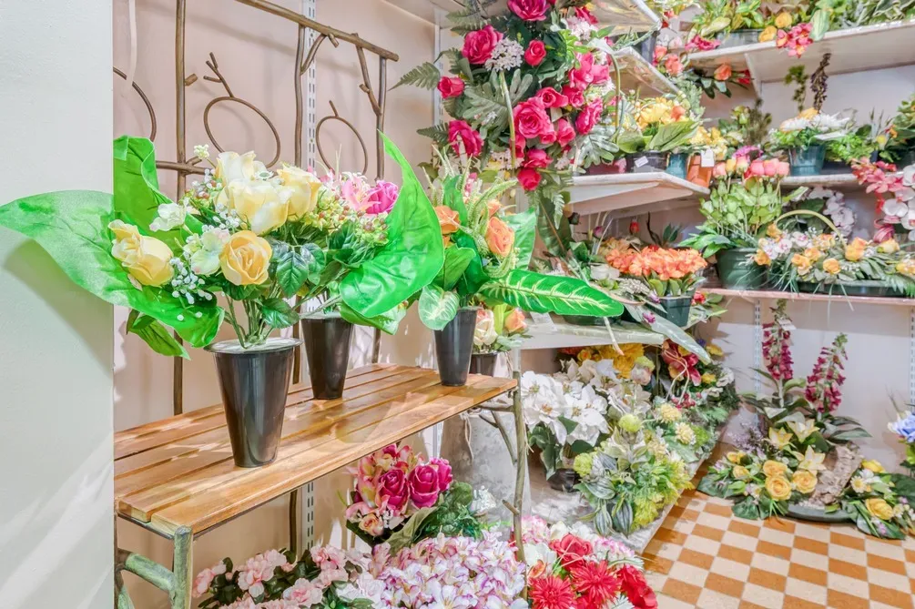 Présentation intérieure de compositions florales artificielles et pots de fleurs.