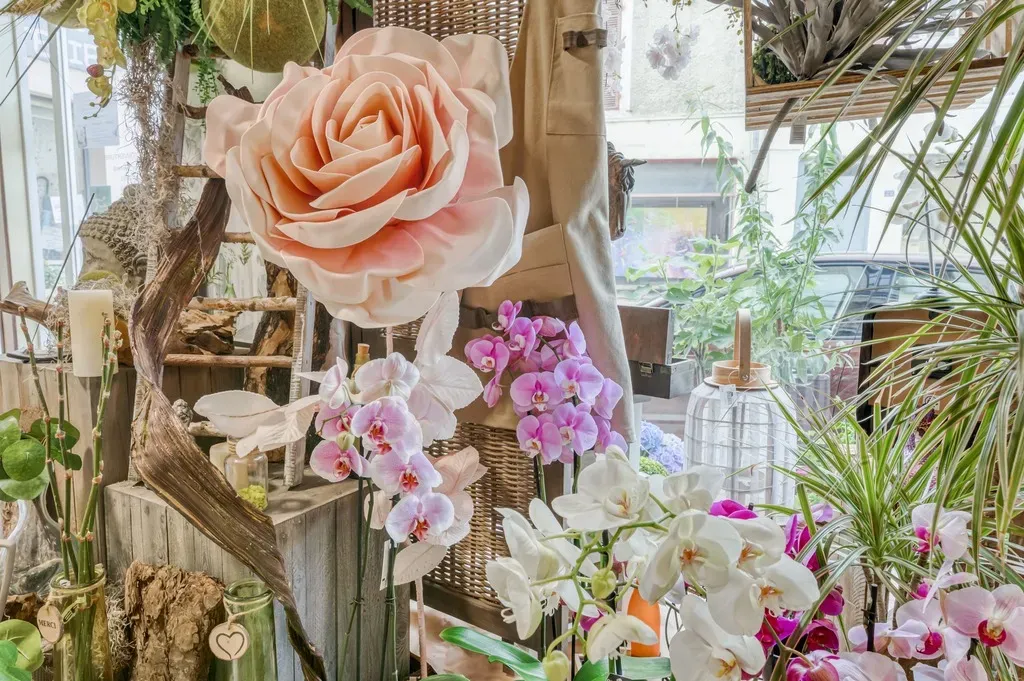 Décoration florale de boutique mettant en valeur une grande rose en tissu et des orchidées.