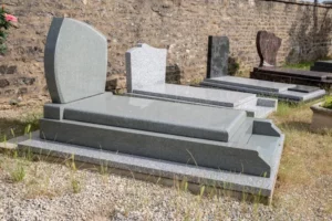 Alignement de pierres tombales et monuments funéraires en granit exposés en extérieur.
