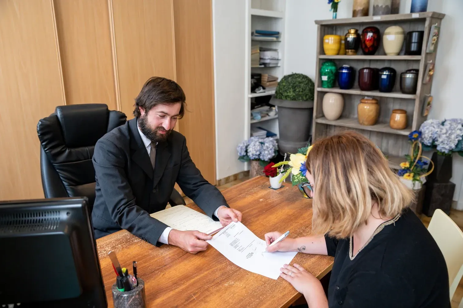 Conseiller funéraire recevant une cliente au bureau pour la signature de documents administrative.