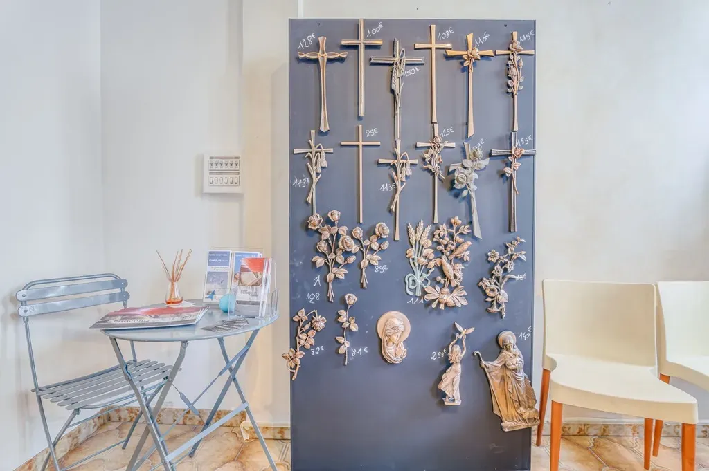 Panneau de présentation d'ornements funéraires en bronze, croix et motifs religieux avec leurs tarifs.